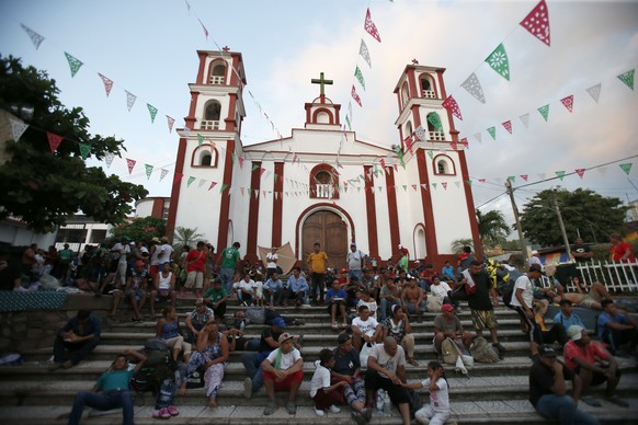 Central American migrants rest on the steps of the church as a thousands-strong caravan slowly making its way toward the U.S. border stops for the night in Pijijiapan, Mexico, Thursday, Oct. 25, 2018. ...