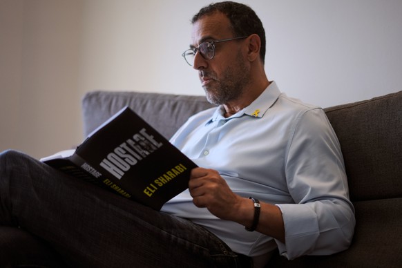 Eli Sharabi, who was abducted during the cross-border attack on Israel on Oct. 7, 2023, and held hostage by Hamas for 16 months, poses with his new book &quot;Hostage&quot; for a photo in Herzliya, Is ...