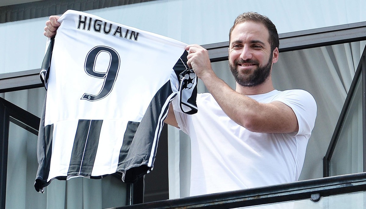 epa05443439 New Juventus striker Gonzalo Higuain poses with his jersey at the team's head office in Turin, Italy, 27 July 2016. Serie A club Juventus signed Higuain from league rival Napoli for 9 ...