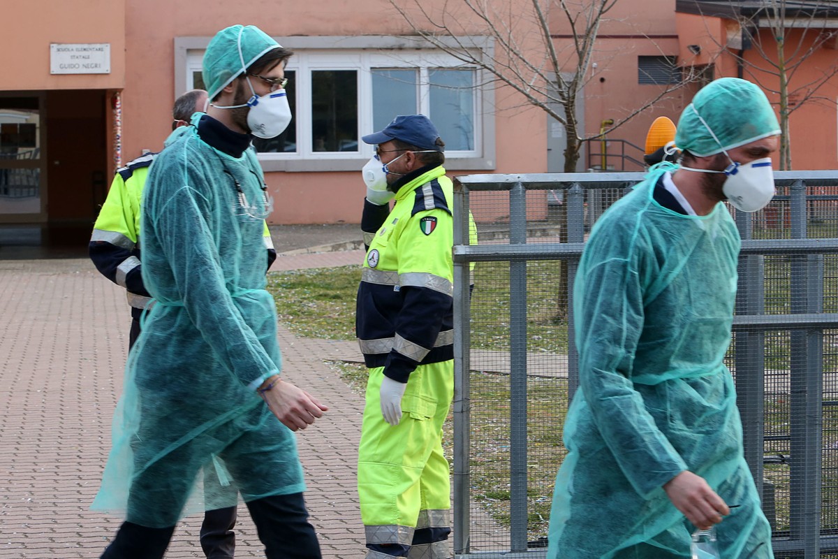 epa08241837 People wear protective face masks in front of a closed elementary school in Vo' Euganeo, Padova, Italy, 23 February 2020. Two deaths from the novel coronavirus sparked fears throughou ...