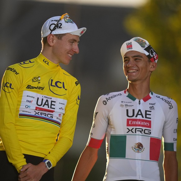 Slovenia's Tadej Pogacar, wearing the overall leader's yellow jersey, celebrates on the podium with Mexico's Isaac Del Toro, right, who came third, after the last stage of the Tour de F ...
