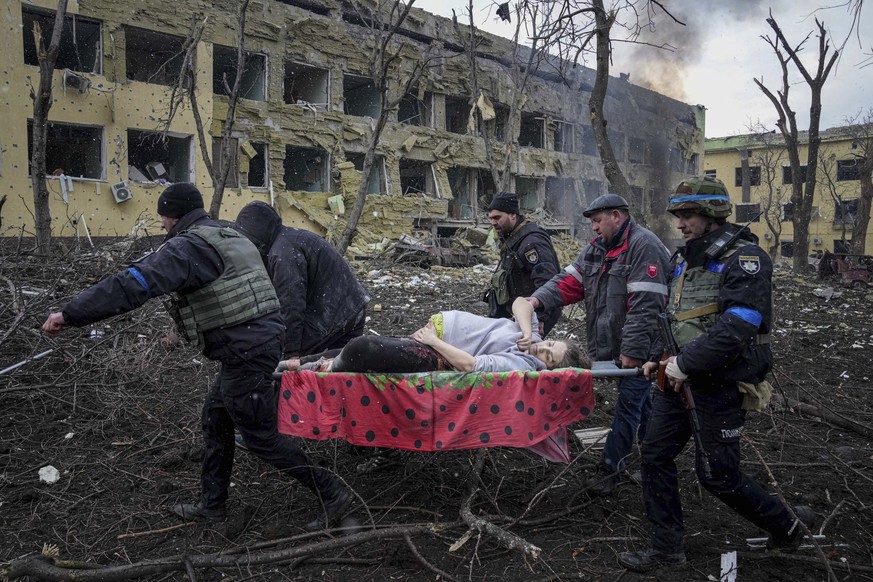 Ukrainian emergency employees and volunteers carry an injured pregnant woman from a maternity hospital that was damaged by shelling in Mariupol, Ukraine, Wednesday, March 9, 2022. (AP Photo/Evgeniy Ma ...