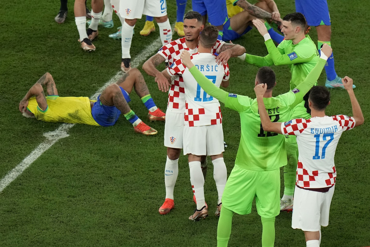 Brazil's Neymar, left, lies dejected on the ground as Croatian players celebrate after their win in the World Cup quarterfinal soccer match against Croatia, at the Education City Stadium in Al Ra ...