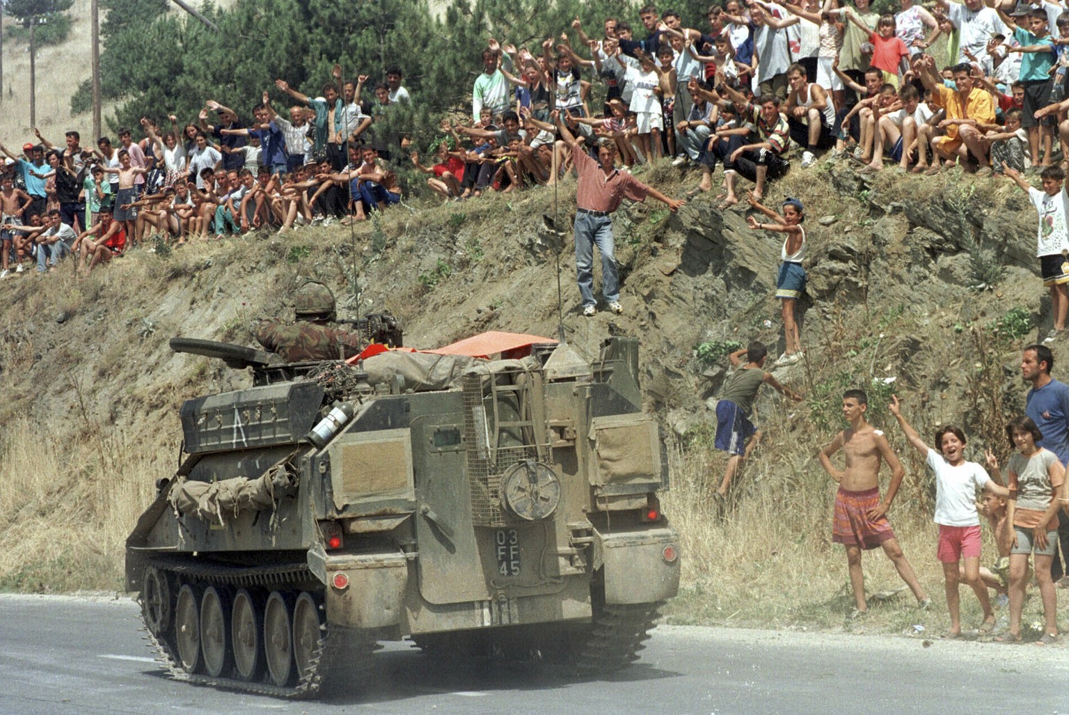 FILE - Ethnic Albanian refugees cheer as a British tank passes next to the Stenkovec refugee camp near Skopje, Macedonia on its way to Kosovo Saturday, June 12, 1999. NATO troops entered Kosovo on Jun ...