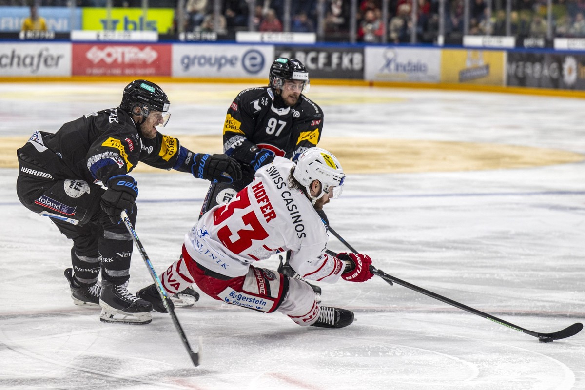 Benoit Jecker (HCFG), links, und Nathan Marchon (HCFG), rechts, kaempfen um den Puck mit Valentin Hofer (SCRJ) im Spiel der Eishockey National League zwischen Fribourg-Gotteron, HCFG, und SC Rapperswi ...