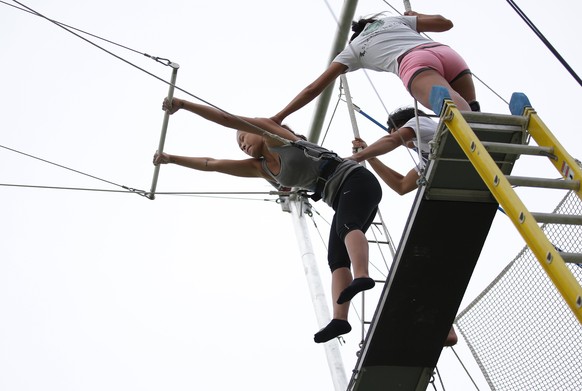 In this photo taken Tuesday, Aug. 12, 2014, a student closes her eyes as she leaves the platform during her first try at the Flying Trapeze Philippines School in suburban Makati, south of Manila, Phil ...
