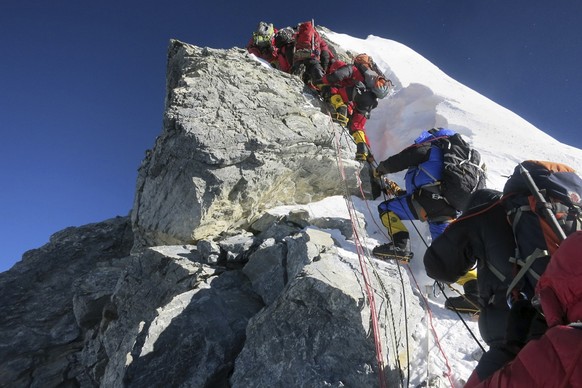 In this image released by mountain guide Adrian Ballinger of Alpenglow Expeditions and taken Saturday, May 18, 2013, climbers navigate the Hillary Step just below the summit of Mount Everest, in the K ...