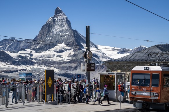 Tourists wearing protective mask are lining up to take the train of Gornergrat Bahn front of the Matterhorn mountain during the coronavirus disease (COVID-19) outbreak, in Zermatt, Switzerland, Wednes ...
