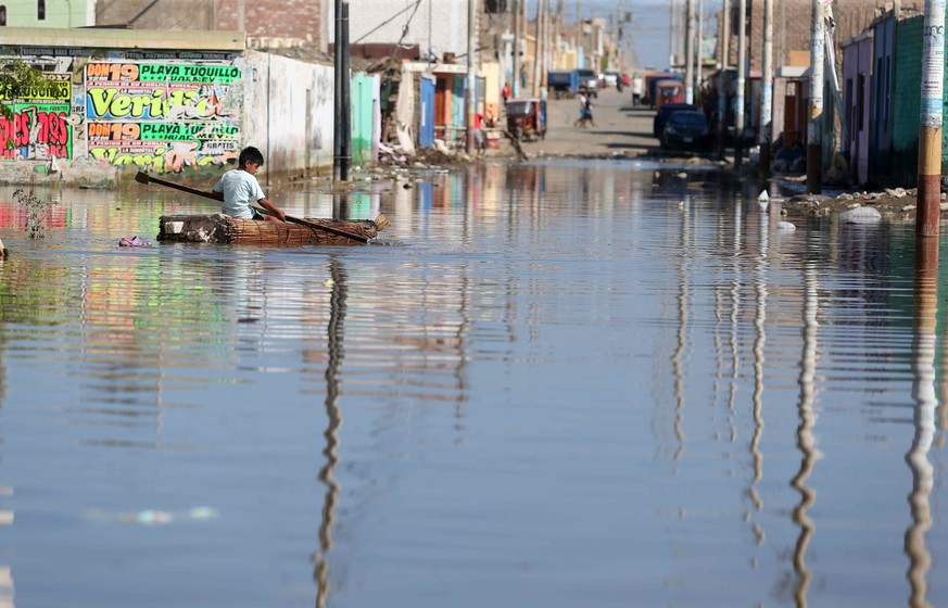 epa05864312 A child paddles a small raft along a flooded street in Huarmay, a coastal region of Ancash, Peru, 22 March 2017. The worst flooding in 20 years is taking its toll on coastal regions of Per ...