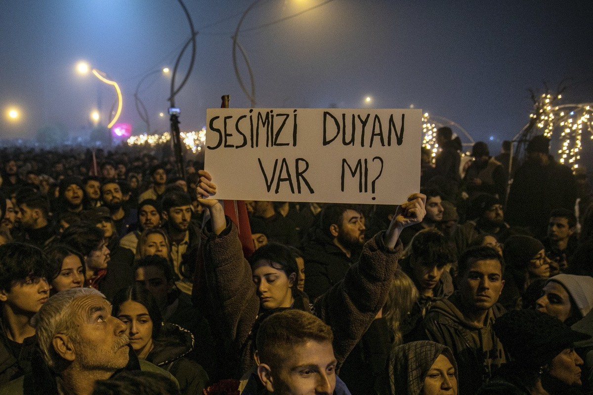 Menschen versammeln sich am Dienstag, dem 6. Februar 2024, in der südtürkischen Stadt Antakya, um den einjährigen Jahrestag des katastrophalen Erdbebens zu feiern. Auf einem Transparent ist zu lesen:  ...