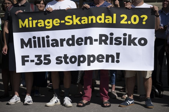 Teilnehmer halten ein Banner in den Haenden fuer den F-35-Stopp, waehrend der Einreichung der Volksinitiative Stop-F-35, am Dienstag, 16. August 2022 in Bern. Die Allianz gegen den F-35 hat ueber 100& ...