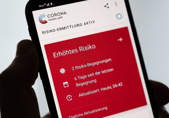 Ein Mann hält ein Smartphone in der Hand, auf dem die Corona-Warn-App der Bundesregierung ein erhöhtes Risiko anzeigt. Foto: Marius Becker/dpa