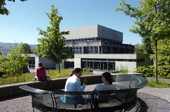 Studenten sitzen am Mittwoch, 25. Mai 2005, vor dem Hauptgebaeude der Universitaet St. Gallen. Die Gebaeude der Universitaet St. Gallen aus den 60er-Jahren muessen umfassend saniert werden. Der Sichtb ...