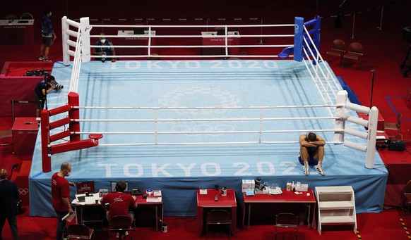 epa09384001 Mourad Aliev of France sits outside the ring in protest after losing his match against Frazer Clarke of Great Britain in the Men&#039;s Super Heavy (+91kg) quarterfinal match of the Boxing ...