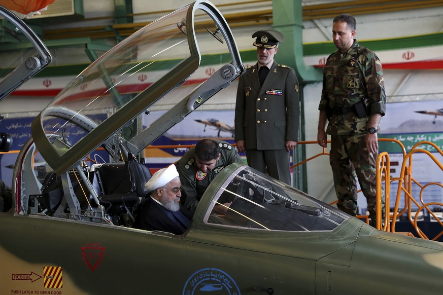 In this photo released by official website of the office of the Iranian Presidency, President Hassan Rouhani is briefed by an air force pilot as he sits in the cockpit of a fighter jet, before an inau ...