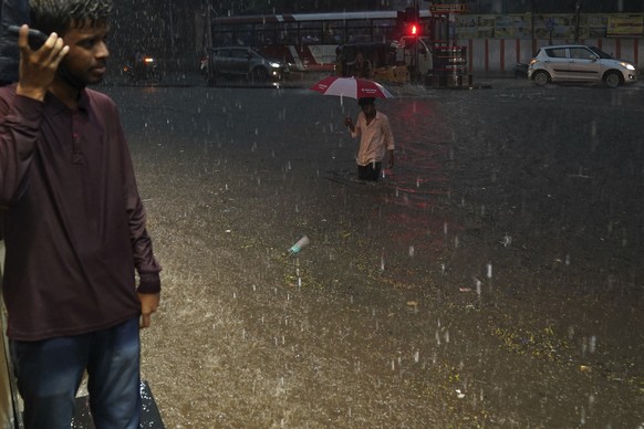 A man wades through flood street in the rain in Hyderabad, India, Tuesday, July 18, 2023. India receives its monsoon rains from June to October. (AP Photo/Mahesh Kumar A.)