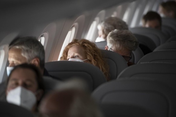 Fluggaeste mit vorgeschriebenen Atemschutzmasken in der Kabine auf einem Flug der Schweizer Fluggesellschaft Helvetic Airways von Zuerich nach Wien mit einem Flugzeug des Typs Embraer E190-E2, fotogra ...