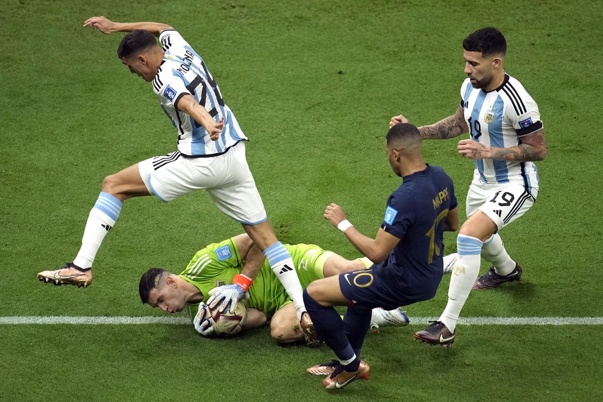Argentina's goalkeeper Emiliano Martinez, bottom, defends as France's Kylian Mbappe, second left, tries to score a goal during the World Cup final soccer match between Argentina and France a ...