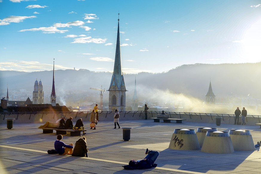 Menschen geniessen den schoenen Wintertag auf der Polyterrasse der ETH in Zuerich am Dienstag, 7. Januar 2014. (KEYSTONE/Walter Bieri)