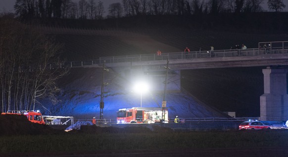 02.04.2020, Baden-Württemberg, Auggen: Feuerwehrfahrzeuge stehen bei dem verunglückten Zug. Der Güterzug, der Lastwagen geladen hatte, ist auf der Rheintalstrecke mit Teilen einer Brücke kollidiert. ( ...