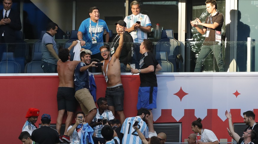 Argentinian soccer former player Diego Armando Maradona, top, stands on the tribune during the group D match between Argentina and Nigeria, at the 2018 soccer World Cup in the St. Petersburg Stadium i ...