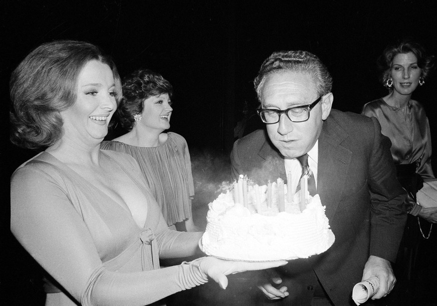Former secretary of state Henry Kissinger blows out the candles on a birthday cake presented to him by actress Millicent Martin, backstage at New York Theater, on May 28, 1977. Watching at rear are ac ...