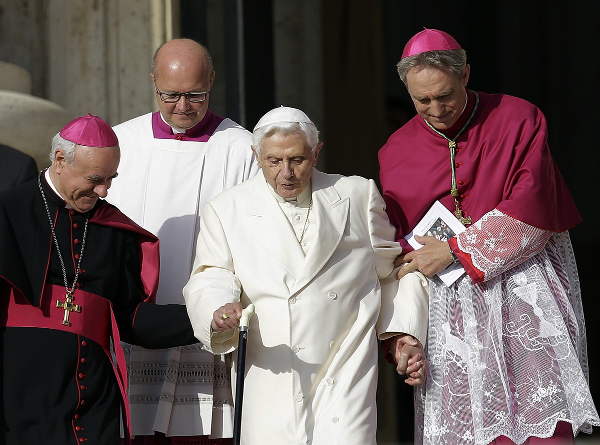 FILE - Pope Emeritus Benedict XVI, center, is helped to walk down the steps by Bishops Vincenzo Paglia, left, and Georg Gaenswein prior to the start of a meeting of Pope Francis with the elderly in St ...