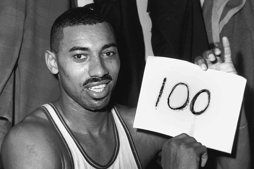FILE - In this March 2, 1962 file photo, Wilt Chamberlain of the Philadelphia Warriors holds a sign reading "100" in the dressing room in Hershey, Pa., after he scored 100 points, as the War ...