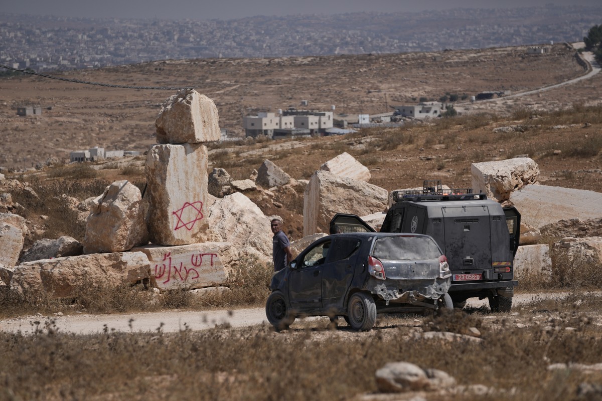 Israeli border police officers talk to Palestinian residents near Hebrew graffiti that reads, "the blood of our brothers," at the site of a rampage by Israeli settlers in the town of As Samu ...