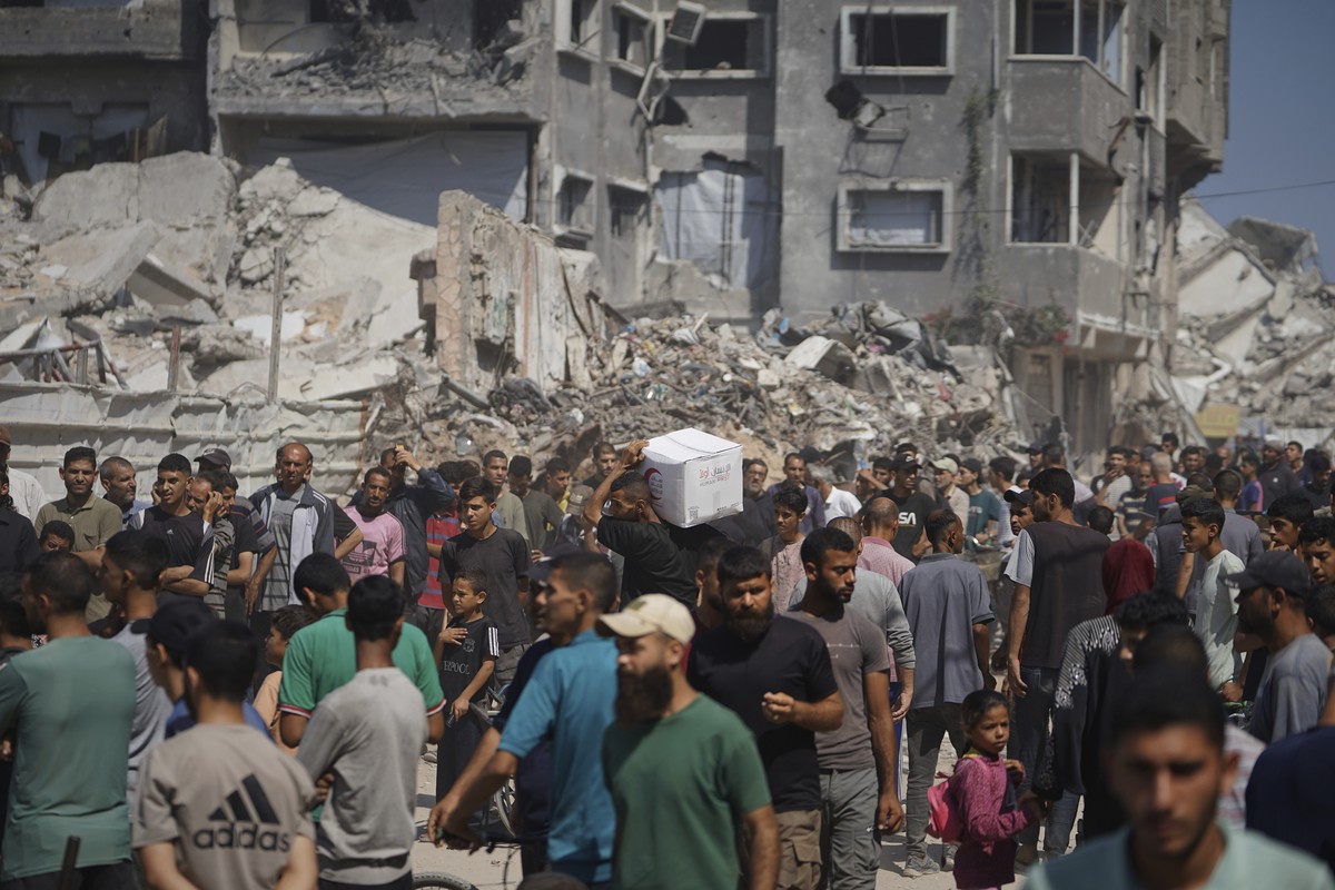 Palestinians receive food parcels distributed by the American Near East Refugee Aid, an organization that provides humanitarian and development aid to the Middle East, in Gaza City, on Thursday, June  ...