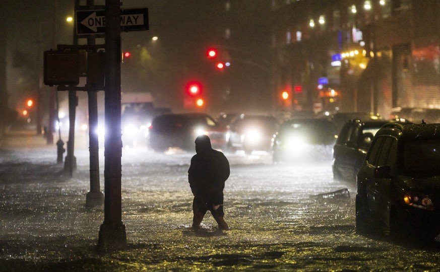 epa09623675 A man navigates a street flooded by heavy rain as remnants of Hurricane Ida hit the area in the Queens borough of New York, New York, USA, 01 September 2021. EPA/JUSTIN LANE