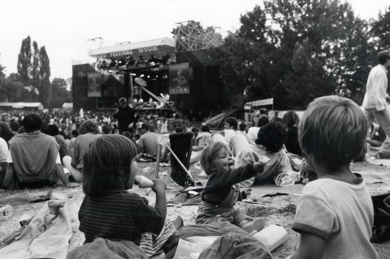 Undatiertes Foto: Kinder sitzen und spielen unter sitzenden Zuschauern am Paléo Festival in Nyon.