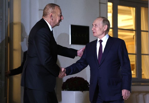 Azerbaijani leader Ilham Aliyev shakes hands with Vladimir Putin.