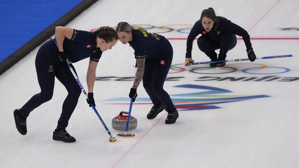 Sweden's Agnes Knochenhauer, left, and Sofia Mabergs sweep the ice during a women's curling semifinal match between Britain and Sweden at the Beijing Winter Olympics Friday, Feb. 18, 2022, in Beijing. (AP Photo/Nariman El-Mofty)