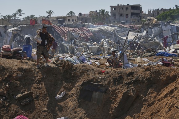A Palestinian walks on the edge of a crater after Israeli military strikes in a tent camp for displaced people near Al-Aqsa Hospital, in Deir al-Balah, Thursday, Aug. 21, 2025. (AP Photo/Jehad Alshraf ...