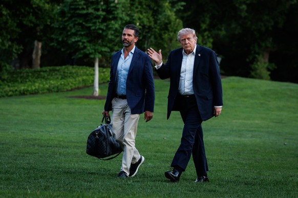 epa12930913 US President Donald Trump (R) walks across the South Lawn towards the White House with his son, Donald Trump Jr. (L), after landing in Marine One in Washington, DC, USA, 03 May 2026. Presi ...