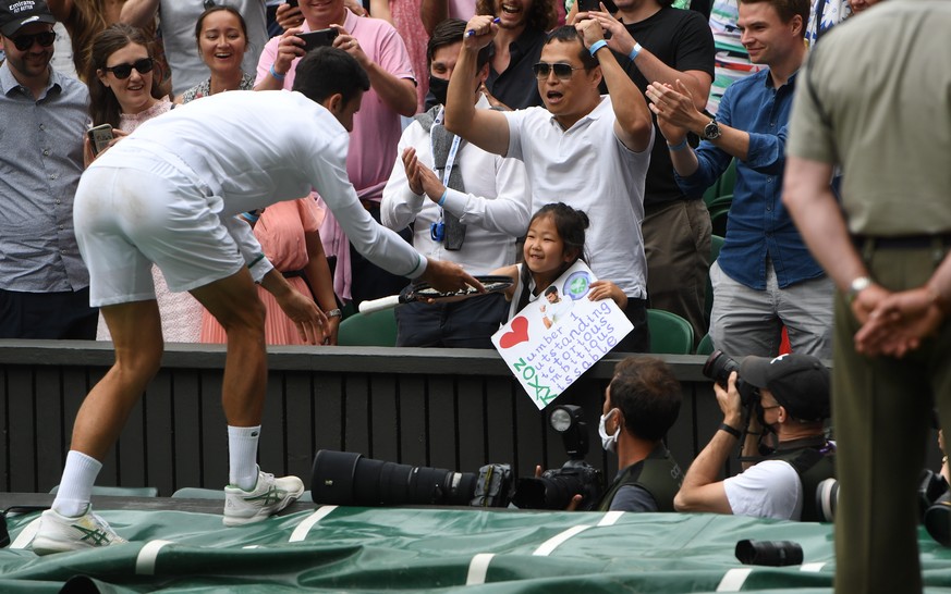 epa09338011 Novak Djokovic of Serbia gives his tennis racquet to a young fan after winning the men&#039;s final against Matteo Berrettini of Italy at the Wimbledon Championships, Wimbledon, Britain 11 ...