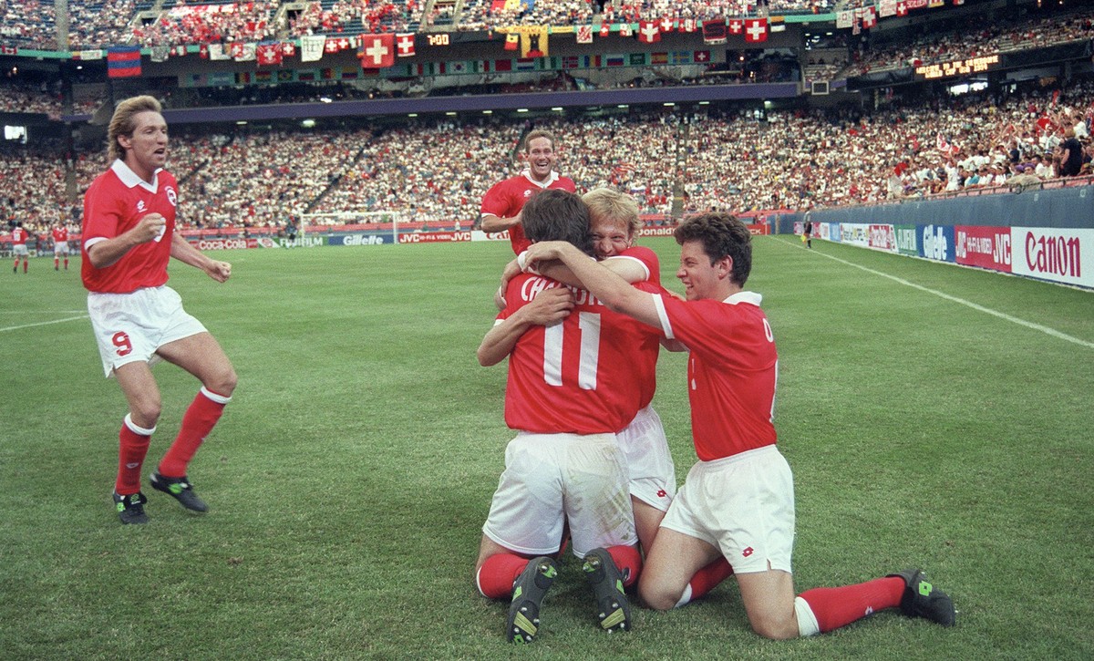 Stephane Chapuisat, Nummer 11, wird nach seinem Tor in der 53. Minute im Vorrundenspiel Schweiz-Rumaenien der Fussball-Weltmeisterschaft am 22. Juni 1994 in Detroit von Adrian Knup, links, Christophe  ...