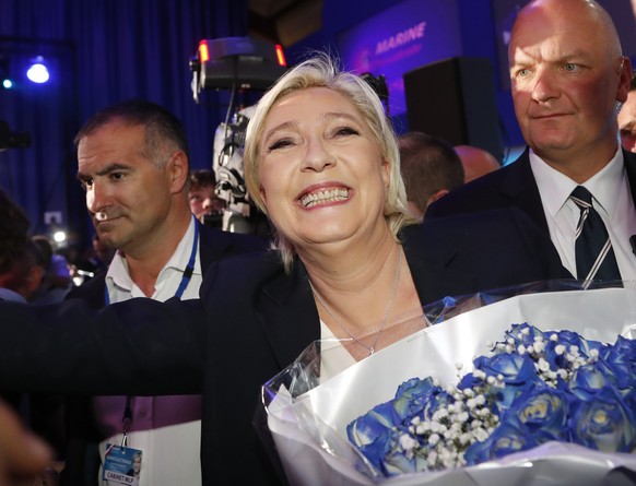 Far-right leader and candidate for the 2017 French presidential election, Marine Le Pen, surrounded by bodyguards, celebrates with supporters while holding a bunch of flowers after exit poll results o ...