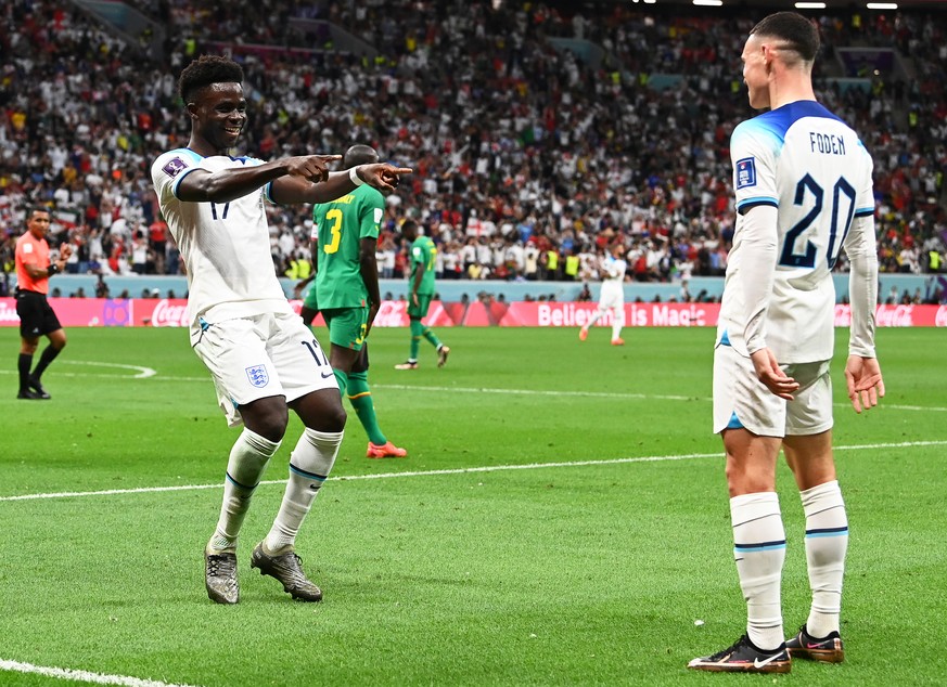 epa10348780 Bukayo Saka (L) of England celebrates with teammate Phil Foden (R) after scoring the 3-0 lead during the FIFA World Cup 2022 round of 16 soccer match between England and Senegal at Al Bayt ...