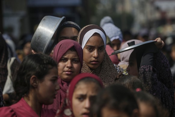 epa11178751 Internally displaced Palestinian children queue up with their pots and containers waiting to receive food provided by Arab and Palestinian donors in Deir Al Balah town, southern Gaza Strip ...
