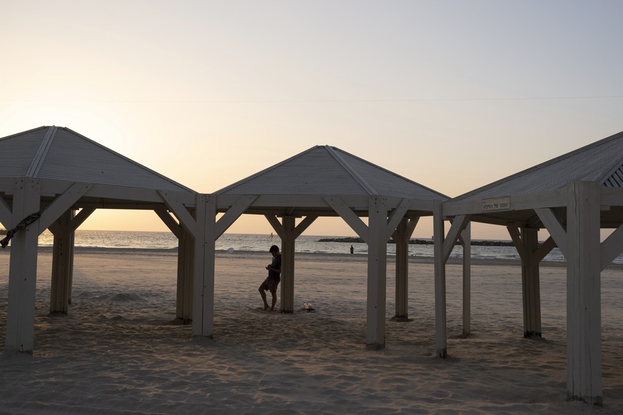 A man looks at his mobile phone at an empty beach in Tel Aviv , Israel, on Wednesday, Oct. 25, 2023. (AP Photo/Petros Giannakouris)