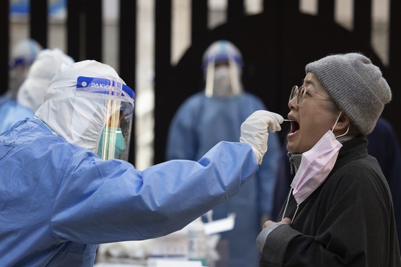 In this photo released by Xinhua News Agency, a medical worker from eastern China&#039;s Anhui Province takes a swab sample from a resident for nucleic acid test at a community in Huangpu District of  ...