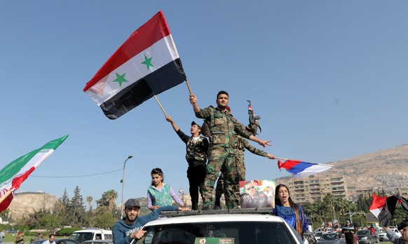 epa06668491 Syrian soldiers wave national flags along with Iranian and Russian flags as people gather to show support for the Syrian government in Umayyad square in Damascus, Syria, 14 April 2018. The ...