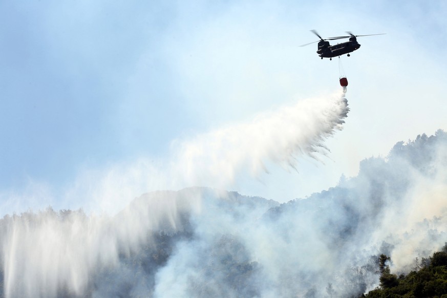 epa09403609 A Chinook helicopter douses a wildfire in Malakassa area, near Athens, Greece, 07 August 2021. Substantial firefighting forces are still battling against fire rekindlings in northern Attic ...