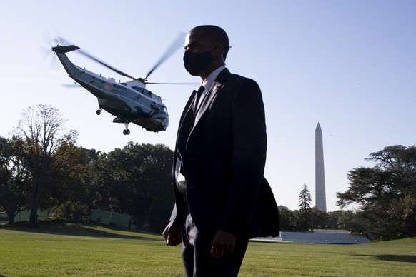 epa09501674 A member of the US Secret Service stands on the South Lawn of the White House as Marine One departs with US President Joe Biden, in Washington, DC, USA, 02 October 2021. Biden travels to W ...