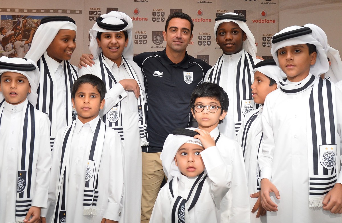 epa04793793 Former FC Barcelona's player Xavi Hernandez poses with young fans during his presentation as new Al-Sadd club player at a press conference in Doha, Qatar, 11 June 2015. The 35-year-ol ...