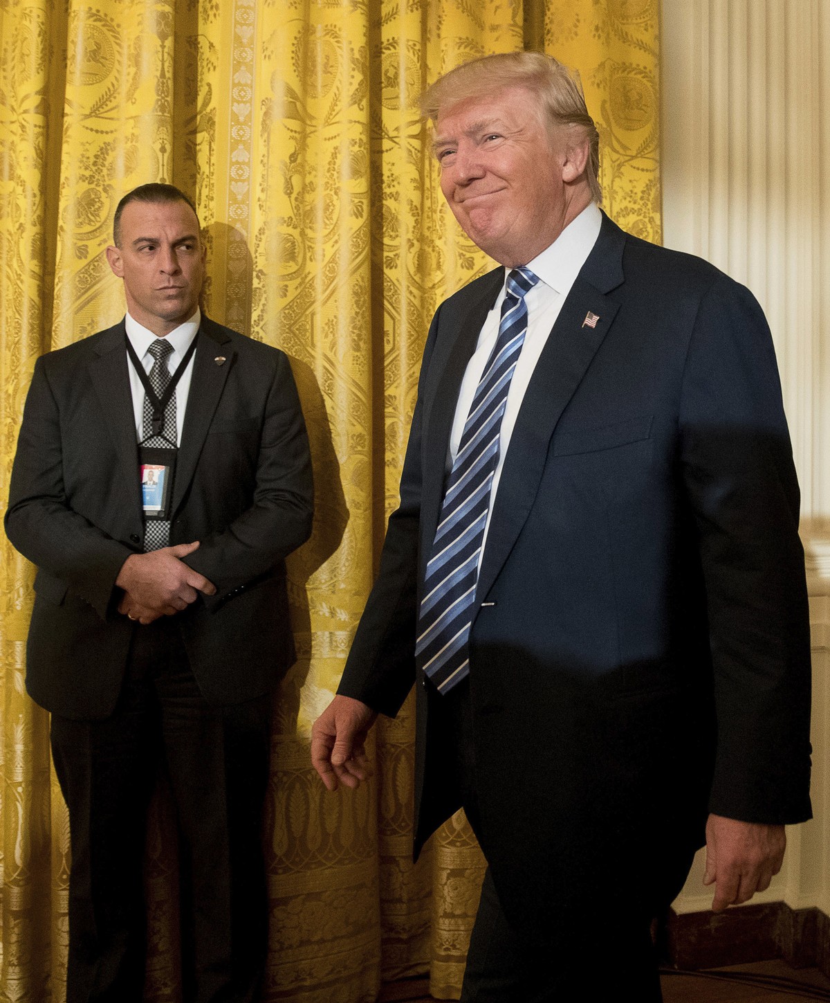 President Donald Trump, center, accompanied by Vice President Mike Pence, right, arrives for a White House senior staff swearing in ceremony in the East Room of the White House, Sunday, Jan. 22, 2017, ...