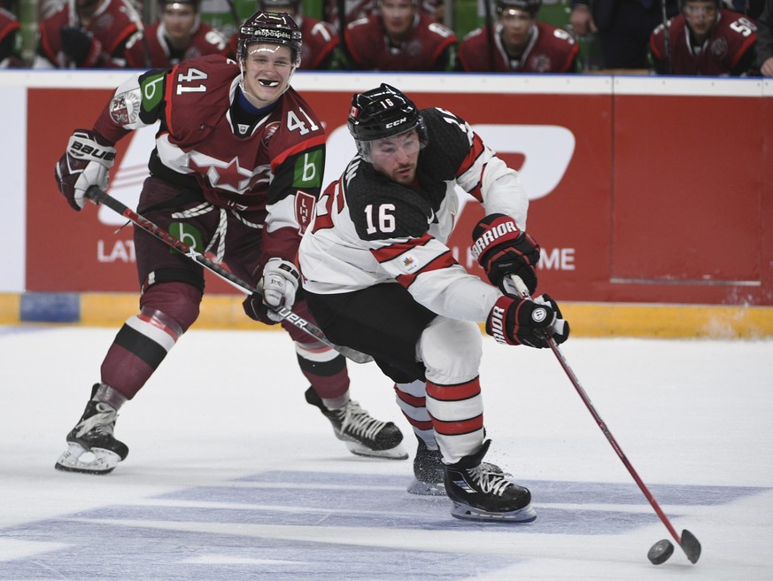 Latvia&#039;s Frenks Razgals, left, and Canada&#039;s Brandon Kozun fight for the puck during an exhibition hockey game in Riga, Latvia, Sunday, Feb. 4, 2018. (AP Photo/Roman Koksarov)