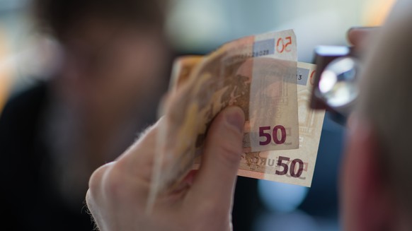 Rainer Elm (Leiter Nationales Analysezentrumam der Deutschen Bundesbank) prueft am 30.03.2017 in Mainz (Rheinland-Pfalz) mit der Lupe zwei 50 Euro-Banknoten. Die deutsche Bundesbank hat ein Analyszent ...